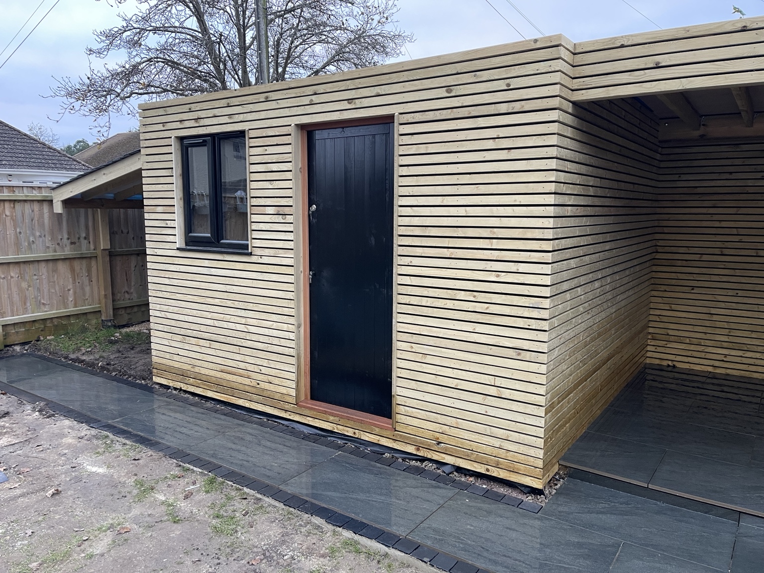 Completed timber-clad garden outbuilding and covered storage